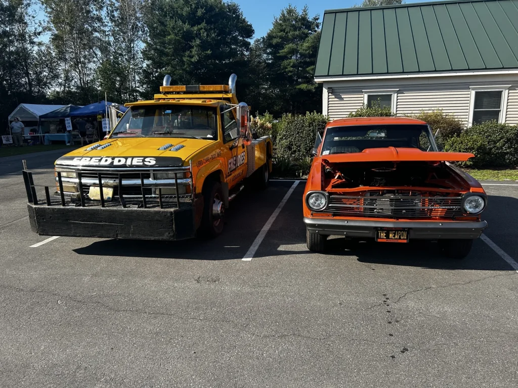 Freddie's yellow wrecker beside an orange 1966–1967 Chevrolet Chevy II Nova at Freddie's Cruise-In 2023.