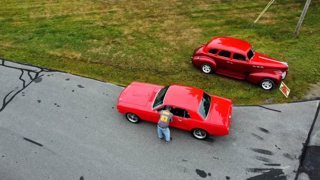 Drone view of two red classic cars at Freddie's Cruise-In 2025.