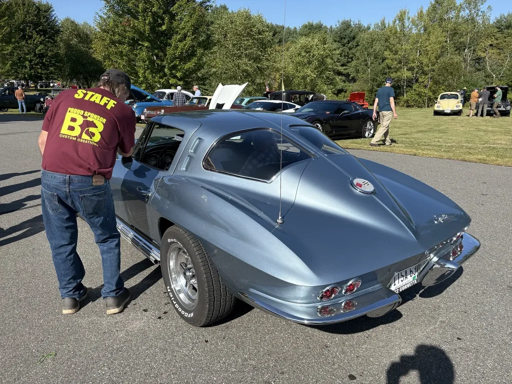 Staff member cleaning a silver split-window Corvette at Freddie's Cruise-In 2026 in Vassalboro, Maine.